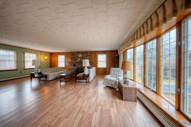 unfurnished living room featuring a baseboard heating unit, light hardwood / wood-style floors, a fireplace, and wooden walls