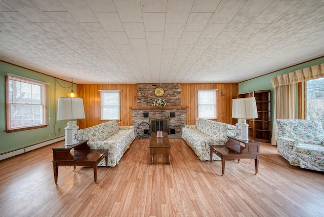 living room with a brick fireplace, a baseboard heating unit, light hardwood / wood-style flooring, and wood walls