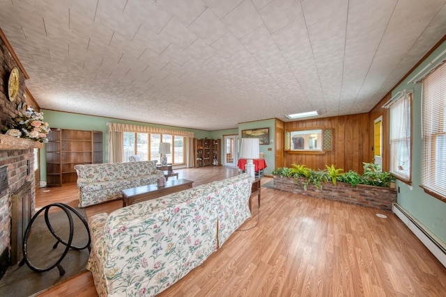 living room with a brick fireplace, wooden walls, light hardwood / wood-style flooring, and a baseboard heating unit