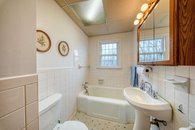 bathroom featuring a bathtub, toilet, tile patterned floors, and tile walls