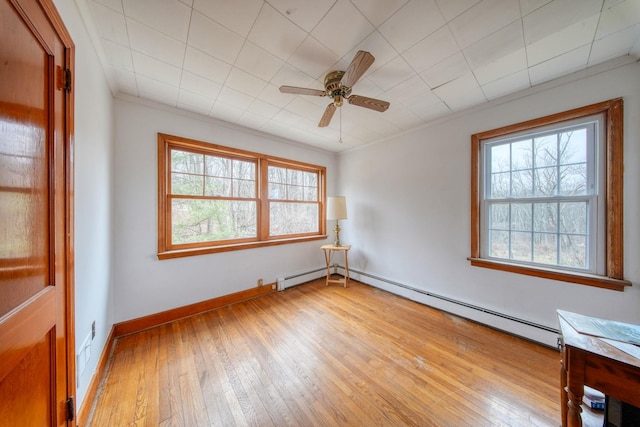 empty room with light wood-type flooring, a healthy amount of sunlight, and baseboard heating