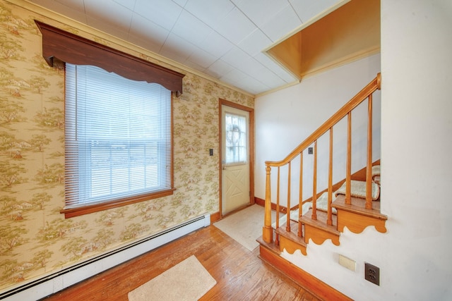 foyer with crown molding, baseboard heating, and hardwood / wood-style floors