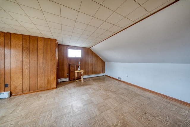 bonus room with wooden walls and a baseboard heating unit