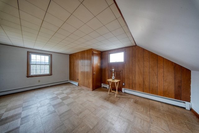 basement featuring baseboard heating, wooden walls, and a healthy amount of sunlight