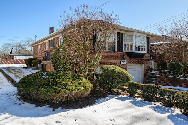 view of front of home featuring brick siding, a chimney, and an attached garage