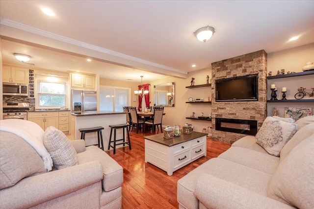 living room featuring a fireplace, ornamental molding, a notable chandelier, and light wood-type flooring