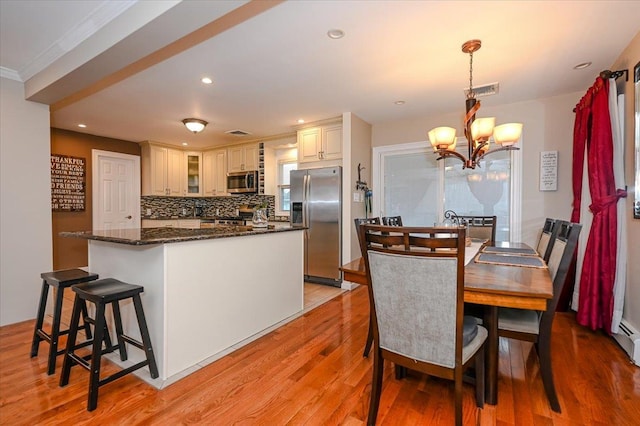 dining space with a notable chandelier and light hardwood / wood-style flooring