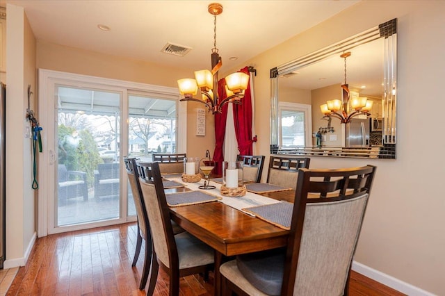 dining room featuring a healthy amount of sunlight, light hardwood / wood-style flooring, and a notable chandelier