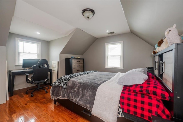 bedroom featuring vaulted ceiling, multiple windows, and hardwood / wood-style floors