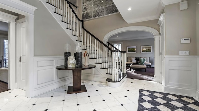 foyer entrance featuring crown molding, plenty of natural light, and decorative columns