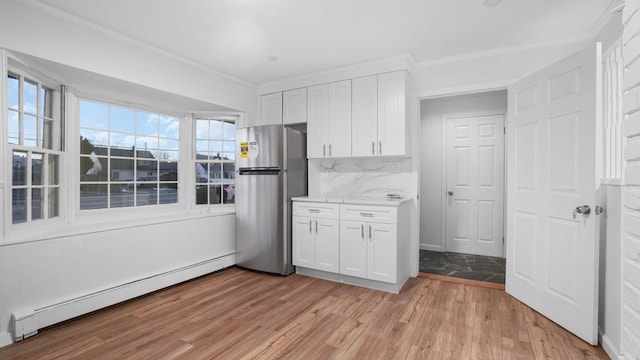 kitchen with light hardwood / wood-style flooring, stainless steel refrigerator, a baseboard heating unit, decorative backsplash, and white cabinets