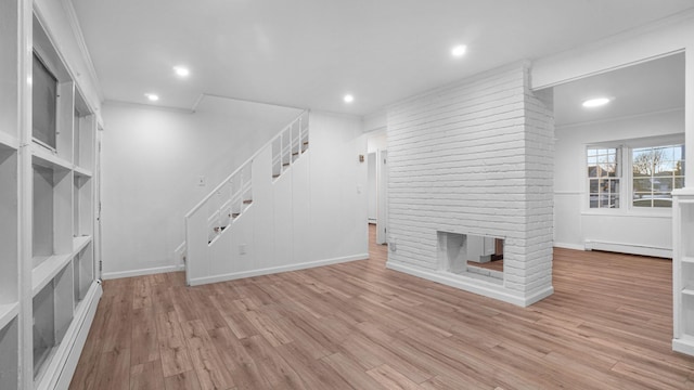 unfurnished living room featuring a baseboard radiator, recessed lighting, a fireplace, wood finished floors, and stairs