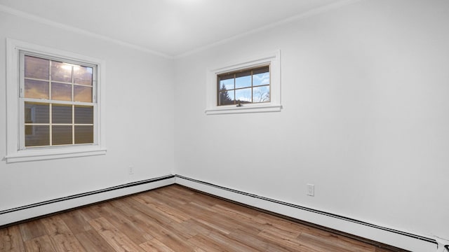 empty room featuring crown molding, baseboard heating, and light hardwood / wood-style flooring