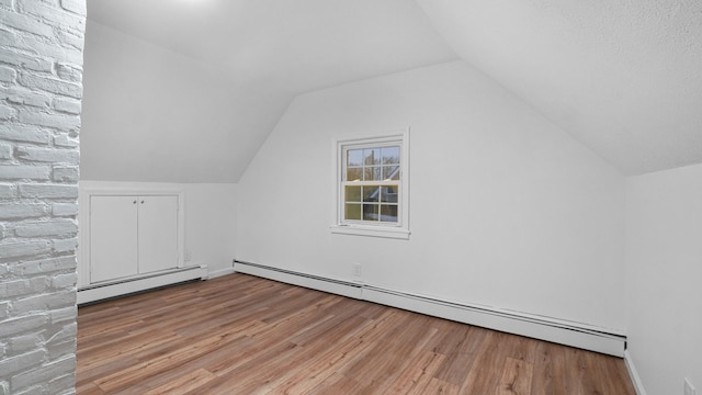 additional living space with lofted ceiling, hardwood / wood-style floors, and baseboard heating