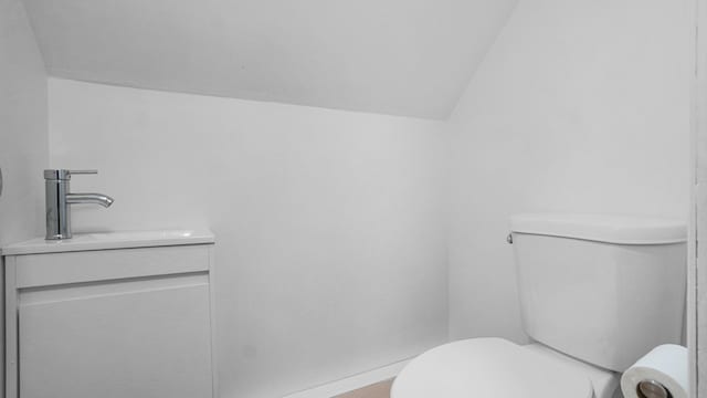 bathroom with vanity, vaulted ceiling, and toilet