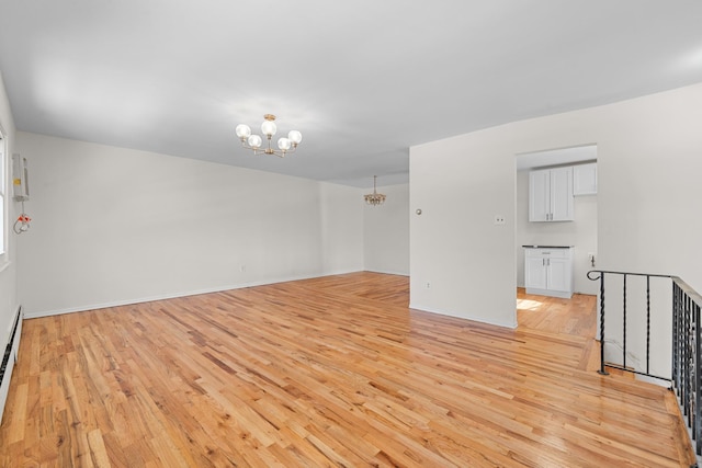 unfurnished room with light wood-type flooring, a chandelier, and a baseboard heating unit