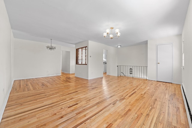 unfurnished living room with a baseboard heating unit, light hardwood / wood-style flooring, and a notable chandelier