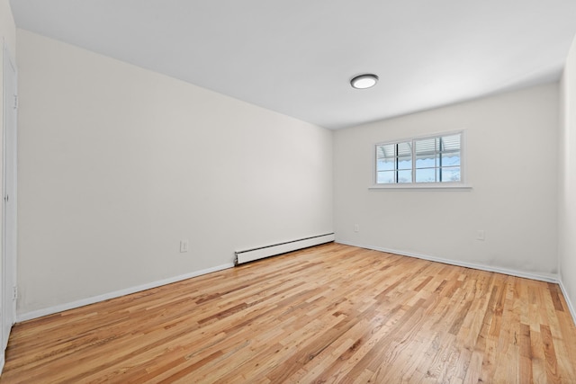 unfurnished room featuring light wood-type flooring and a baseboard heating unit