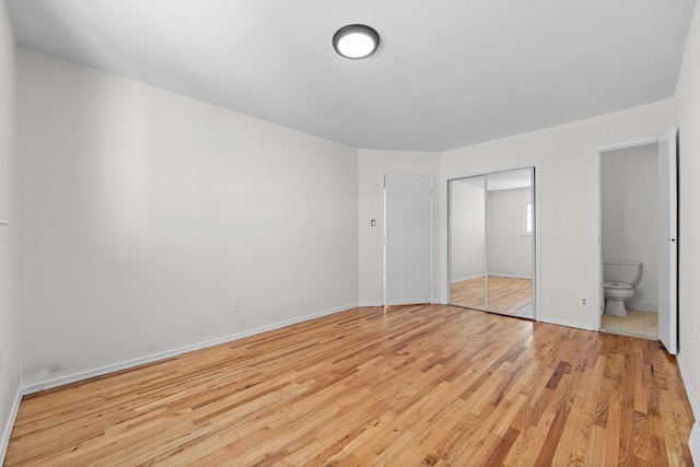 unfurnished bedroom with a closet, connected bathroom, and light hardwood / wood-style floors