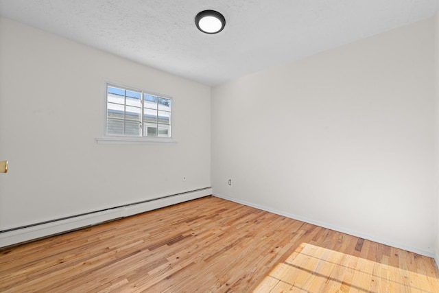 empty room with a textured ceiling, baseboard heating, and light hardwood / wood-style flooring