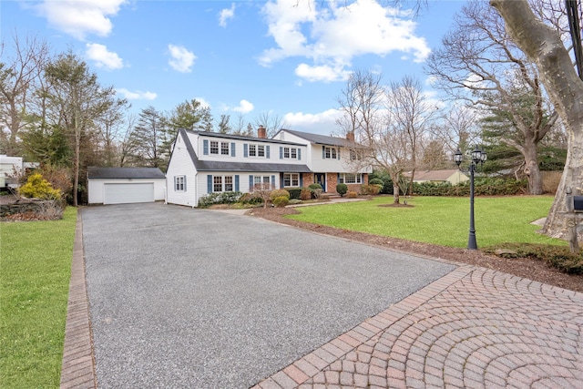 view of front of home with a front yard, an outdoor structure, and a garage