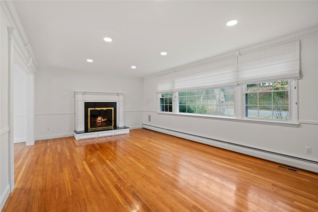 unfurnished living room with light wood-type flooring, a healthy amount of sunlight, and a baseboard radiator