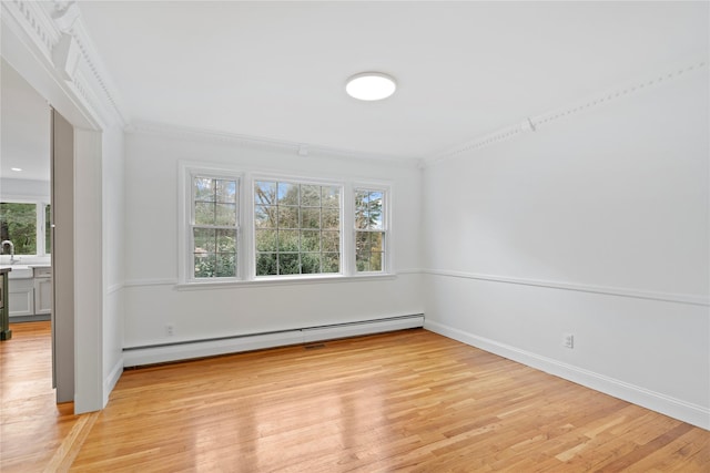 empty room with light wood-type flooring, a baseboard heating unit, and ornamental molding