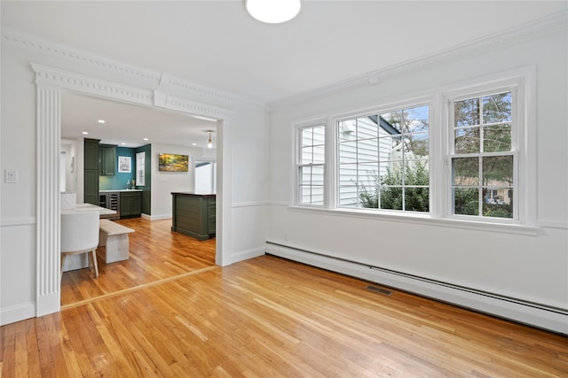 unfurnished living room featuring sink, crown molding, wood-type flooring, and a baseboard radiator