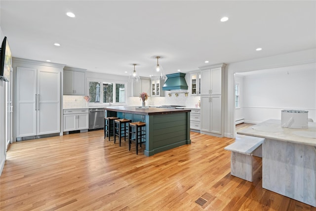 kitchen featuring light hardwood / wood-style floors, a center island, stainless steel appliances, and custom range hood