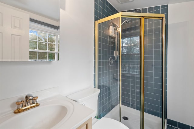 bathroom with toilet, vanity, and a shower with shower door