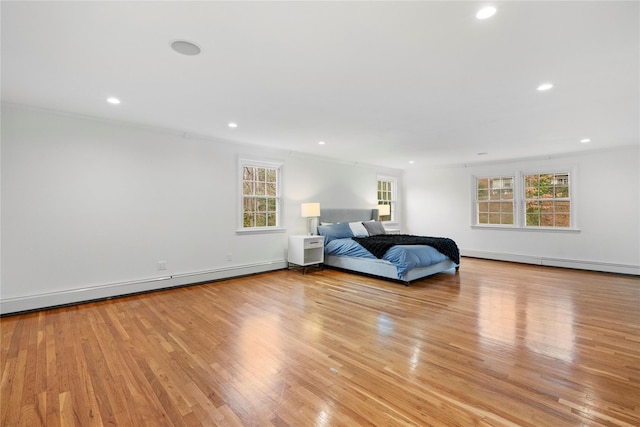 unfurnished bedroom with light wood-type flooring, baseboard heating, and multiple windows