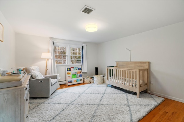 bedroom featuring a nursery area and light hardwood / wood-style flooring