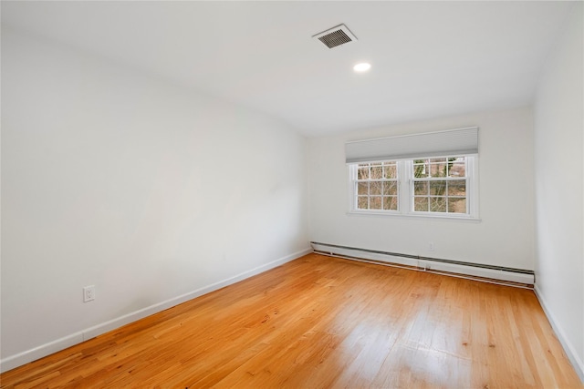 empty room with baseboard heating and light hardwood / wood-style floors