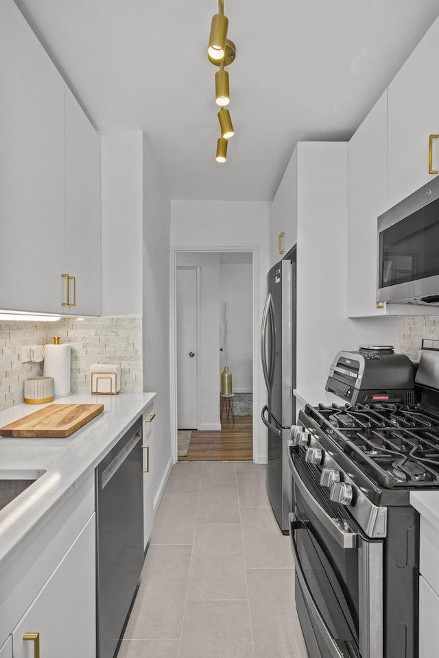 kitchen featuring light tile patterned flooring, white cabinetry, decorative backsplash, and appliances with stainless steel finishes