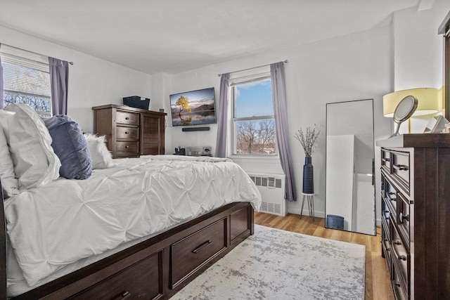 bedroom with radiator and light hardwood / wood-style floors