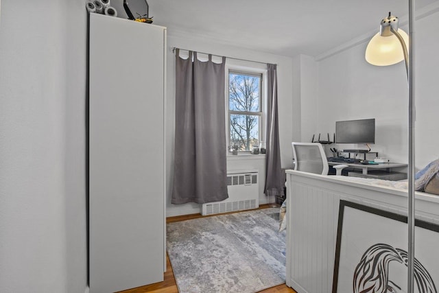 bedroom featuring radiator heating unit and light wood-type flooring