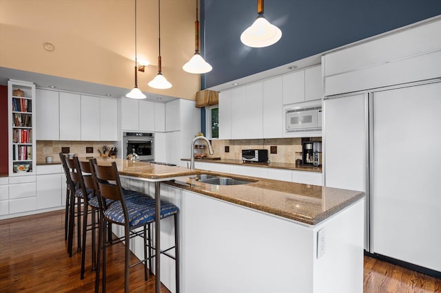 kitchen with sink, pendant lighting, white cabinets, and built in appliances