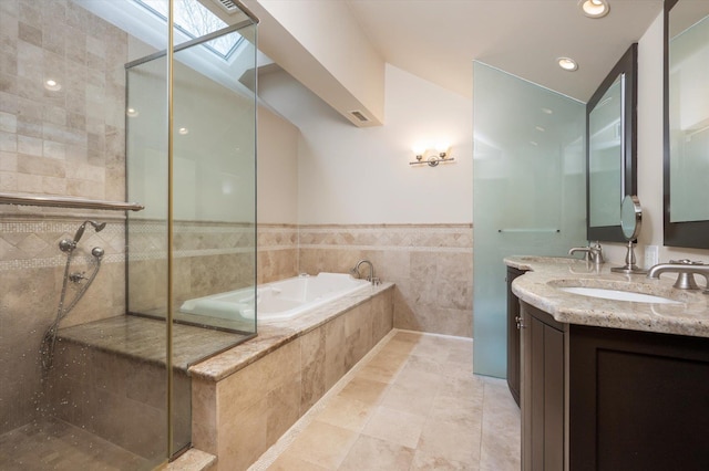 bathroom featuring tile walls, vanity, a skylight, and shower with separate bathtub