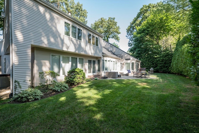 rear view of property with a lawn, central AC, and a patio