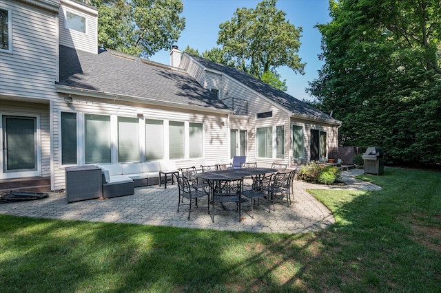 rear view of house with a lawn, an outdoor living space, and a patio area