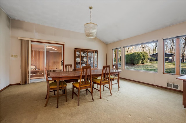 dining area with vaulted ceiling and light carpet