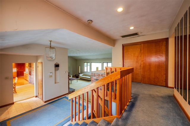 hall featuring a chandelier, carpet flooring, and lofted ceiling