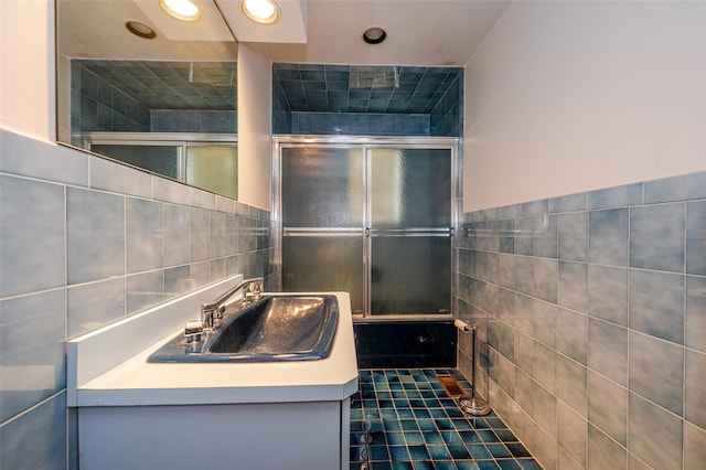 bathroom featuring bath / shower combo with glass door, vanity, tile patterned floors, and tile walls