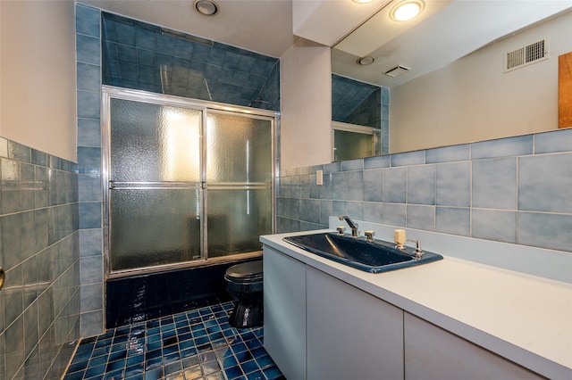 full bathroom featuring toilet, combined bath / shower with glass door, tile walls, tile patterned floors, and vanity