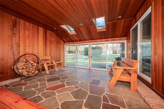 unfurnished room featuring wood walls, lofted ceiling with skylight, and wood ceiling