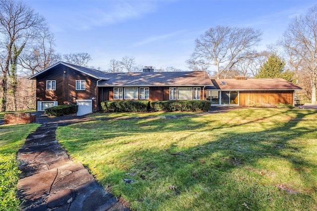 back of house featuring a garage, concrete driveway, a lawn, and a chimney