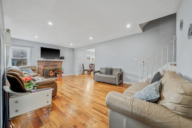 living room with a brick fireplace and light hardwood / wood-style floors