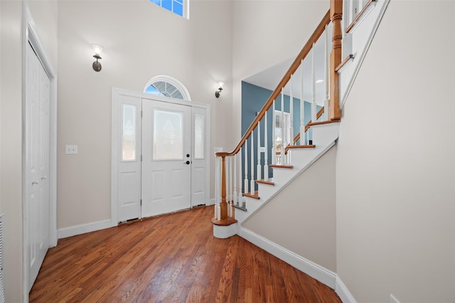 entryway with hardwood / wood-style flooring and a towering ceiling