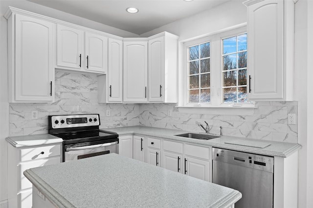 kitchen with tasteful backsplash, appliances with stainless steel finishes, sink, and white cabinets