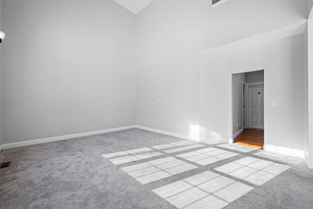 carpeted empty room featuring high vaulted ceiling